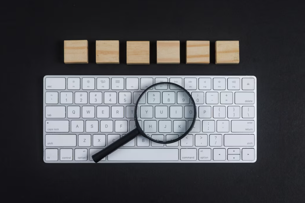 white keyboard and magnifying glass on it, wooden cubes above