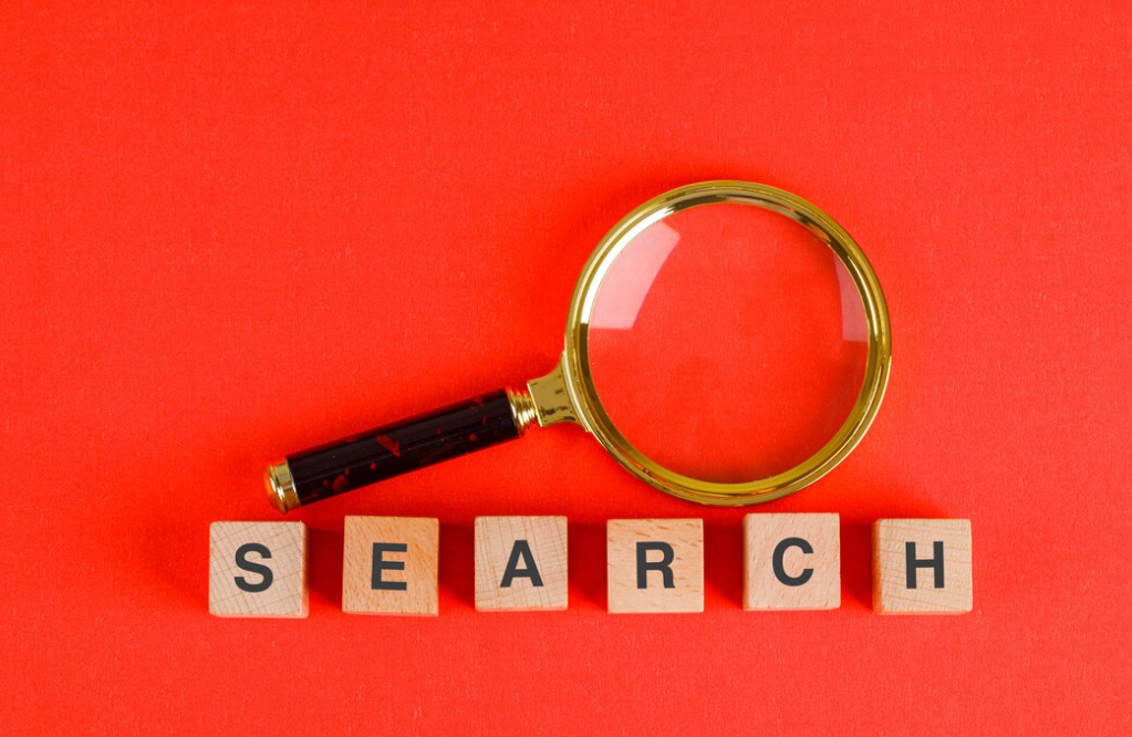 magnifying glass and word search on wooden cubes on red background