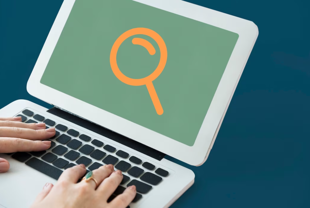 hands with ring on the finger on the laptop keyboard, the magnifying glass on the screen